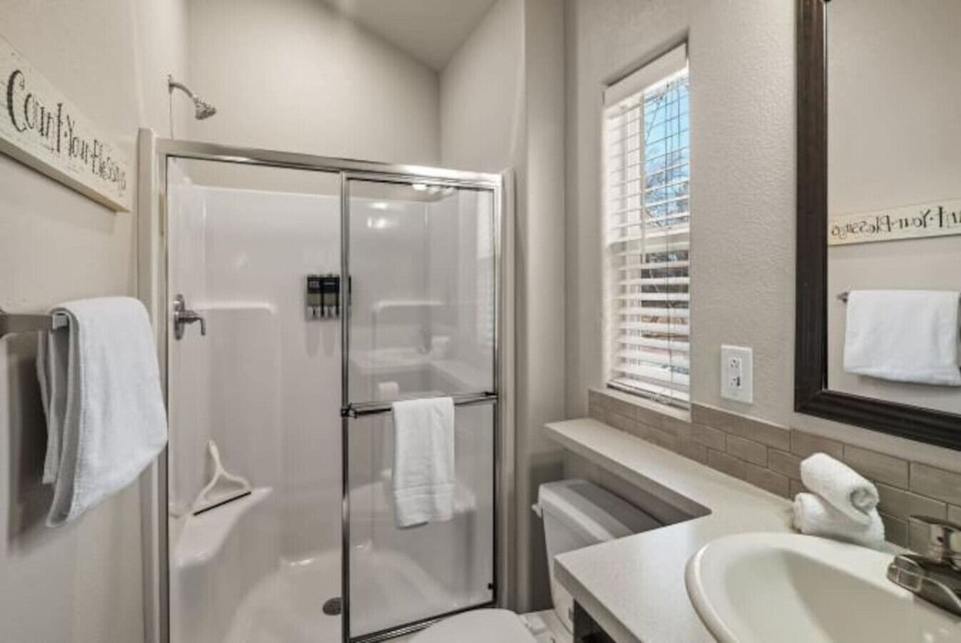 A modern bathroom with a glass shower enclosure, a sink, and a vanity.