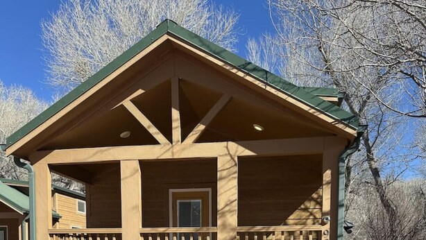 A wooden cabin with a porch, a door, and a window.