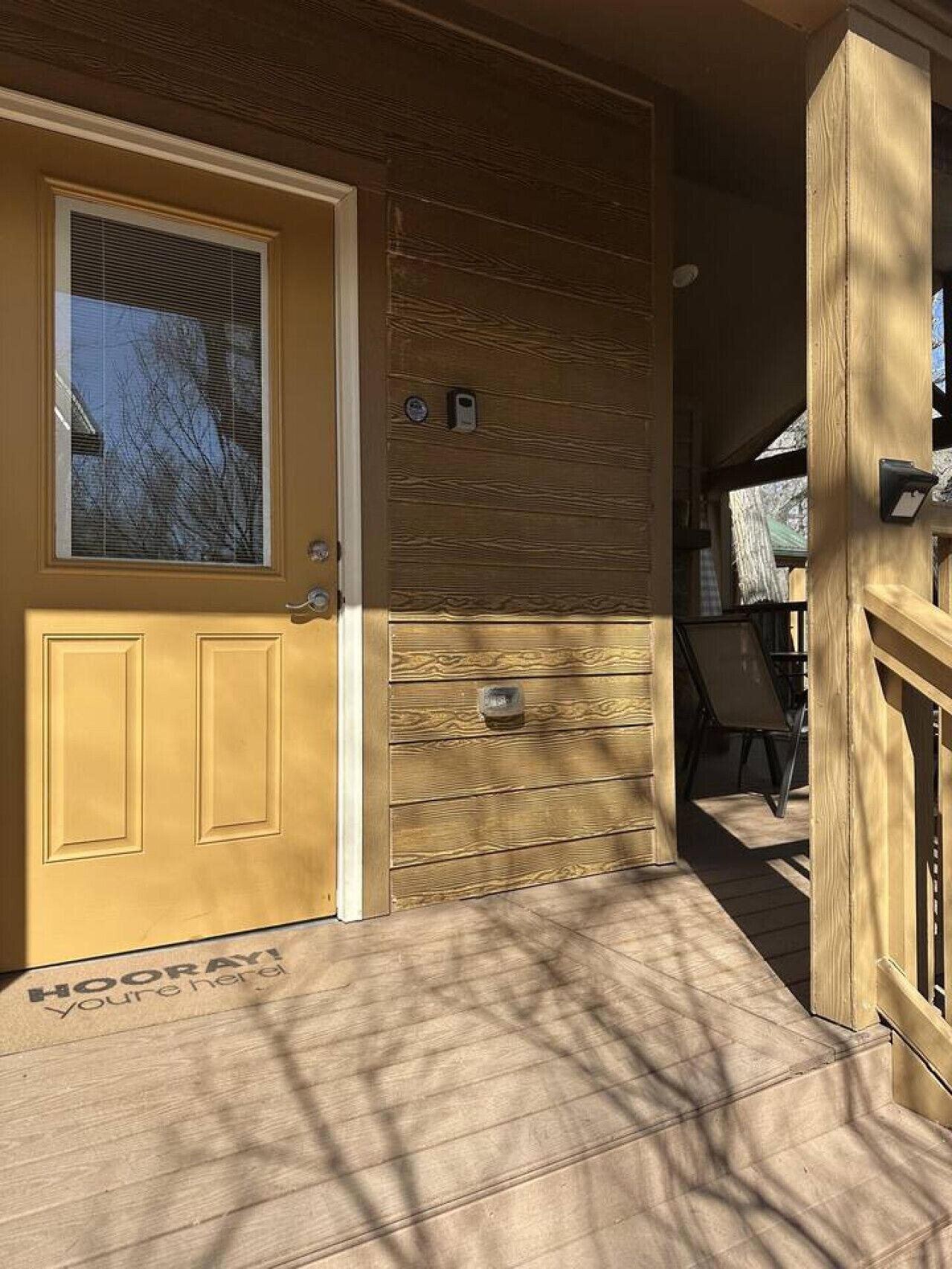 A wooden door with a window, a mailbox, and a welcome mat with text.