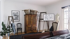 Ein Zimmer mit einem Holzschrank, einer Puppenfigur und Kunstwerken an den Wänden.