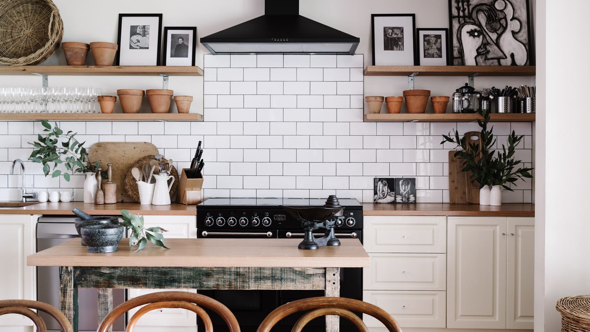 Een keuken met een witte betegelde spatwand, houten planken en een centraal eiland met een kookplaat.