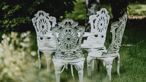 Espace extérieur aménagé avec des chaises et des tables en métal ouvragé, installé sur une pelouse.