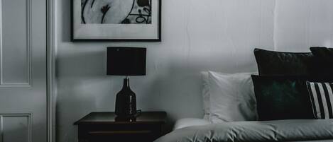 A bedroom with a bed, a nightstand, a lamp, and a framed picture on the wall.