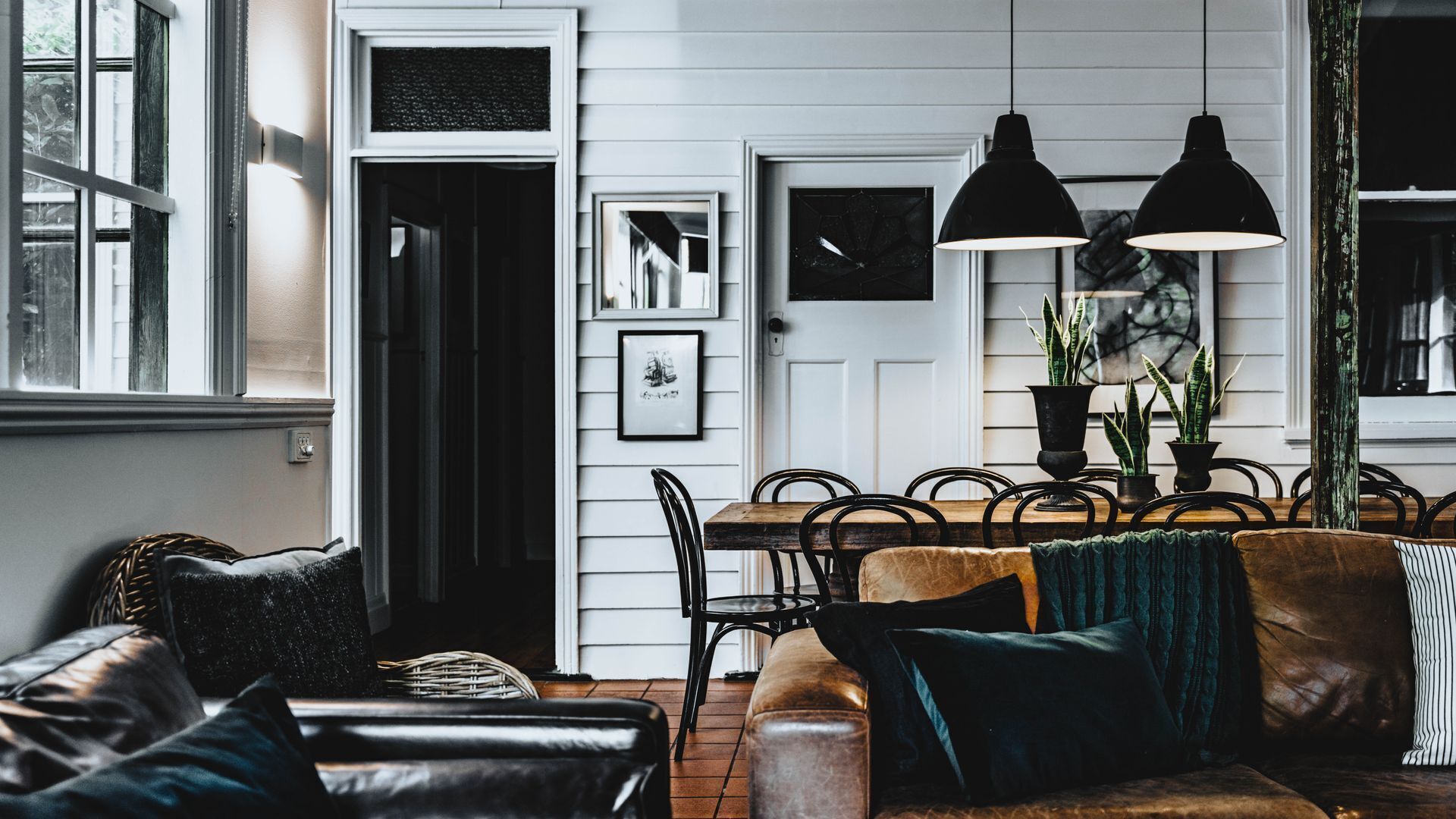 Una sala acogedora con un sofá de cuero, una mesa de comedor de madera y sillas, e iluminación colgante.