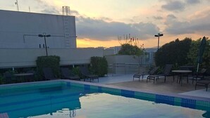 Ein Pool auf dem Dach mit Liegestühlen und Blick auf den Sonnenuntergang.