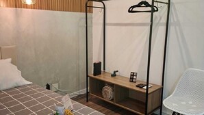 Ein Hotelzimmer mit einem Bett, einem Nachttisch mit Lampe, einem Sessel und einem Kleiderschrank mit Spiegel.