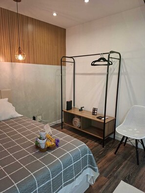 Une chambre d’hôtel comprenant un lit, une table de chevet avec une lampe, une chaise et une armoire avec un miroir.
