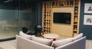 Ein modernes Wohnzimmer mit einer Couch, Sesseln, einem Fernseher und einer Holzhocker-Anordnung.