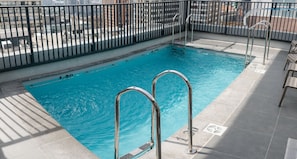 Una piscina con escaleras de metal y un borde con azulejos.