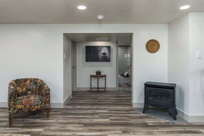 A hallway with a patterned armchair, a small table, and a fireplace. - The Center Street Hideaway- Private Basement Suite (Pocatello)