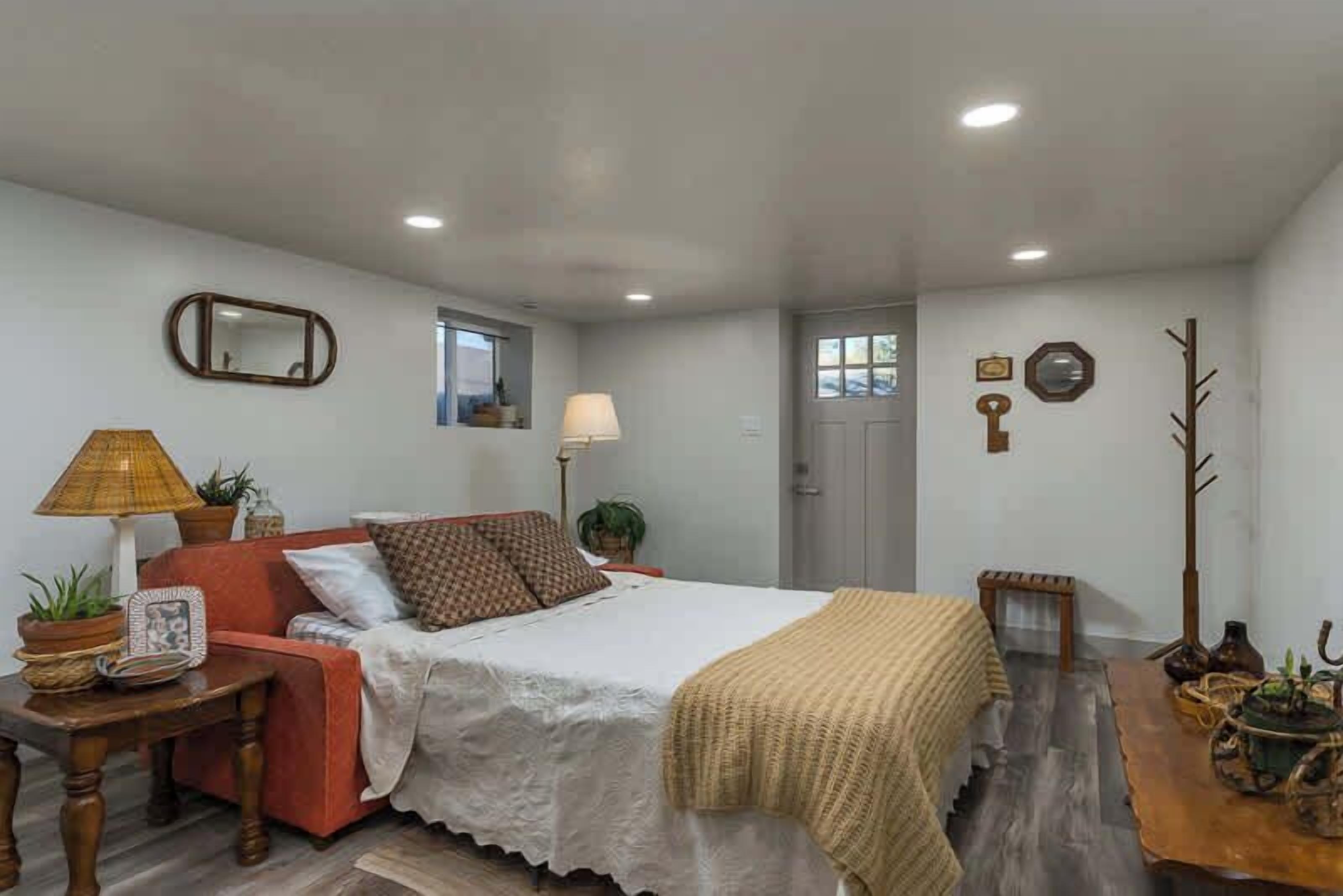 Un dormitorio con cama, mesita de noche, lámpara y una ventana pequeña.