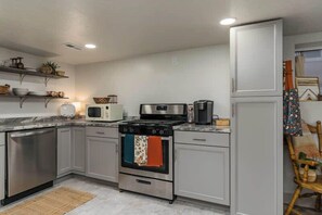 Una cocina con electrodomésticos de acero inoxidable, microondas, cafetera y refrigerador.