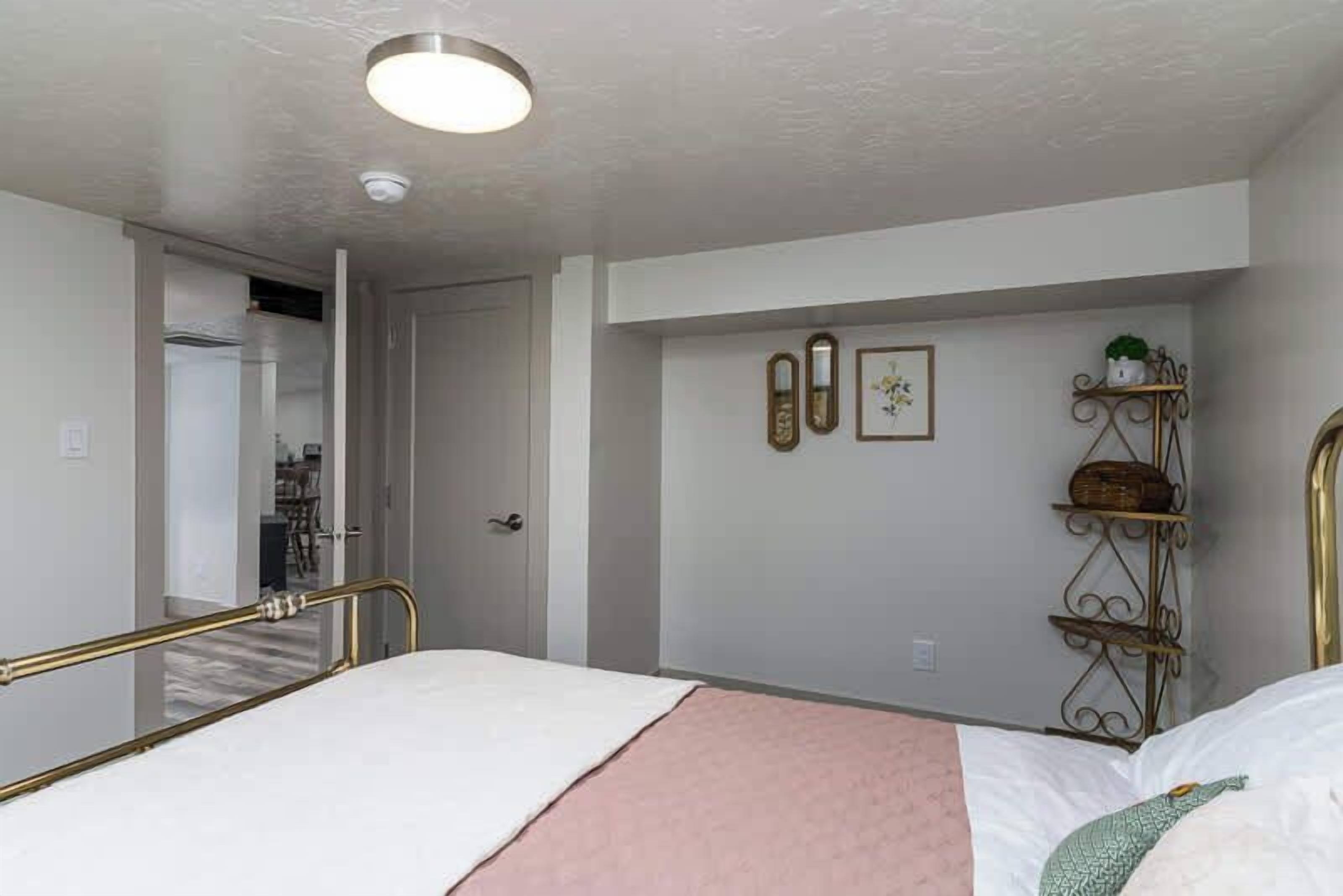 Een slaapkamer met een bed, een nachtkastje, een wandplank en een deur.