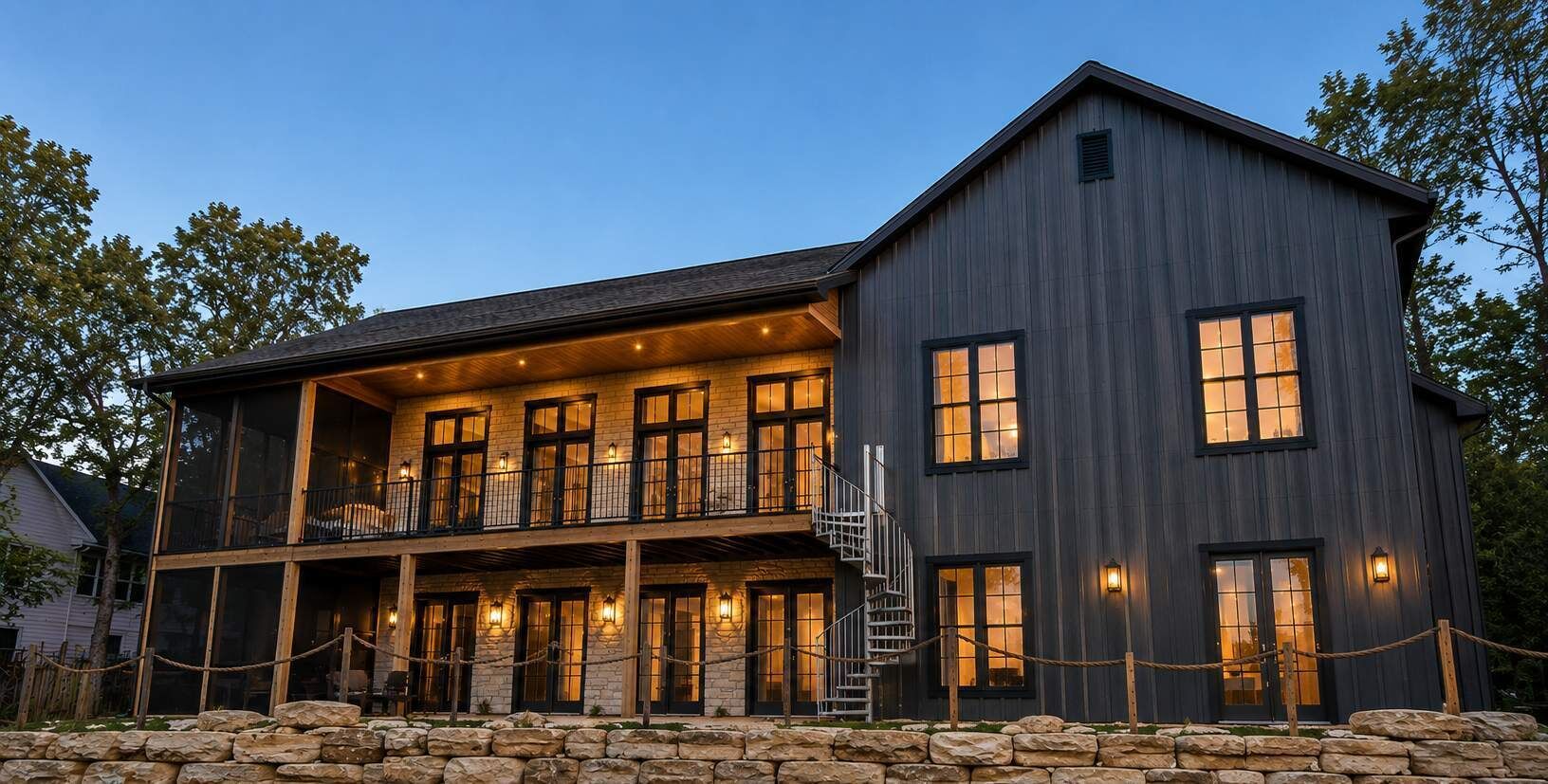 A two-story building with a balcony, stone foundation, and multiple windows.
