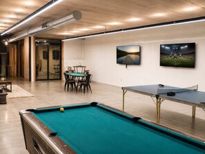 A billiards table, a pool table, and a dining area with chairs and a table. - The Shipwreck Shack - Fall Getaway | Hot Tub • Sleeps 18 (Mauston)