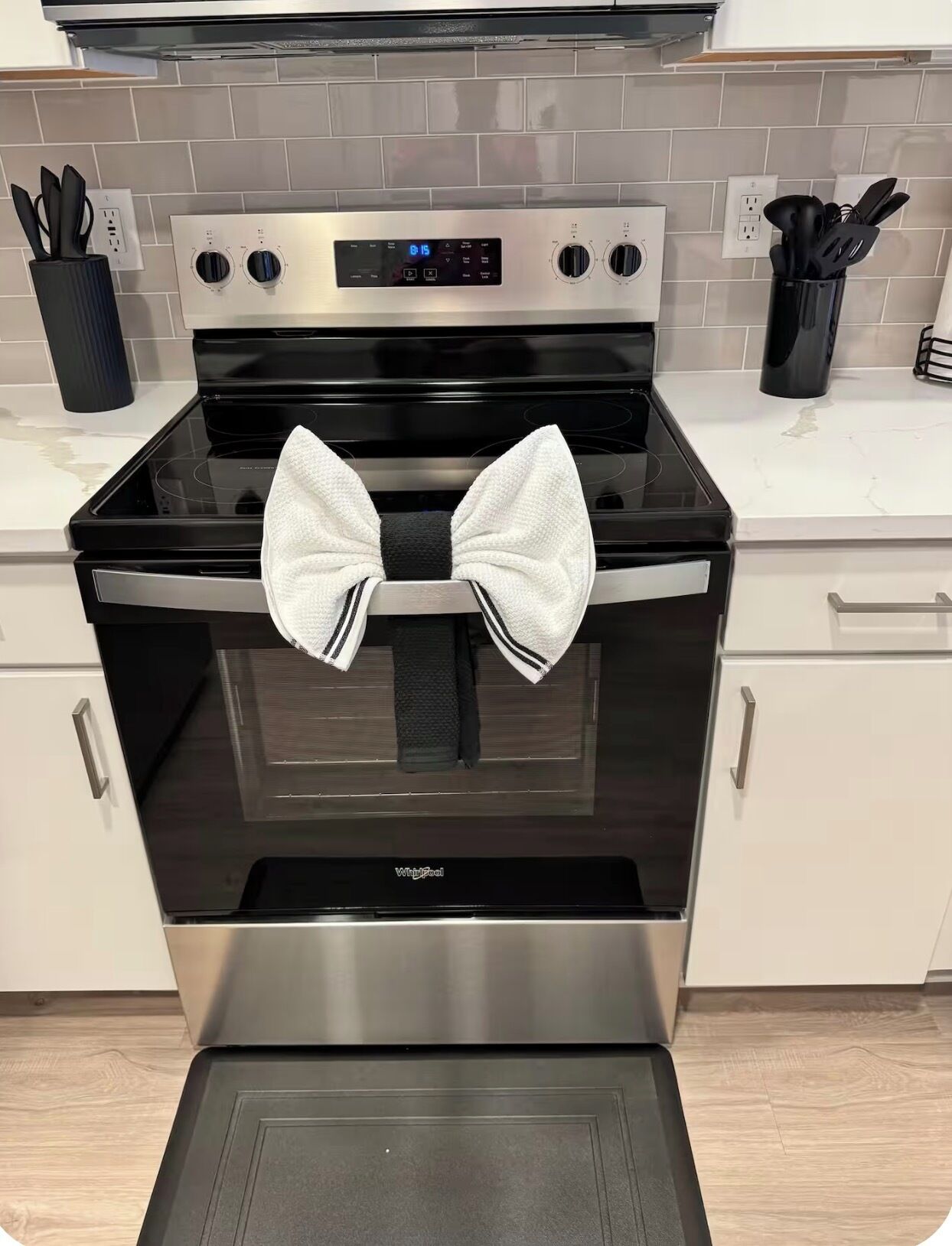 A kitchen with a stainless steel oven, a digital clock, and a black stovetop.