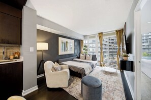 A modern bedroom with a bed, a chair, a desk, and a large window with curtains. - DT Gem near the CN Tower & Rogers Centre! (Toronto)