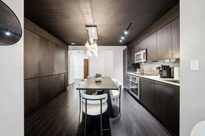 Een moderne keuken met donker houten kastjes, roestvrijstalen apparatuur en een centraal eiland met zitplaatsen.
