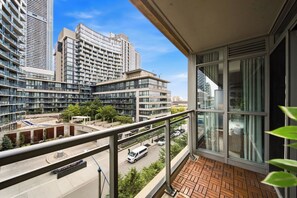 Ein Balkon mit Blick auf eine Stadtlandschaft, darunter hohe Gebäude und eine Straße mit Autos.