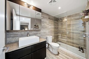 A modern bathroom with a large mirror, a sink, a toilet, and a shower area. - DT Gem near the CN Tower & Rogers Centre! (Toronto)