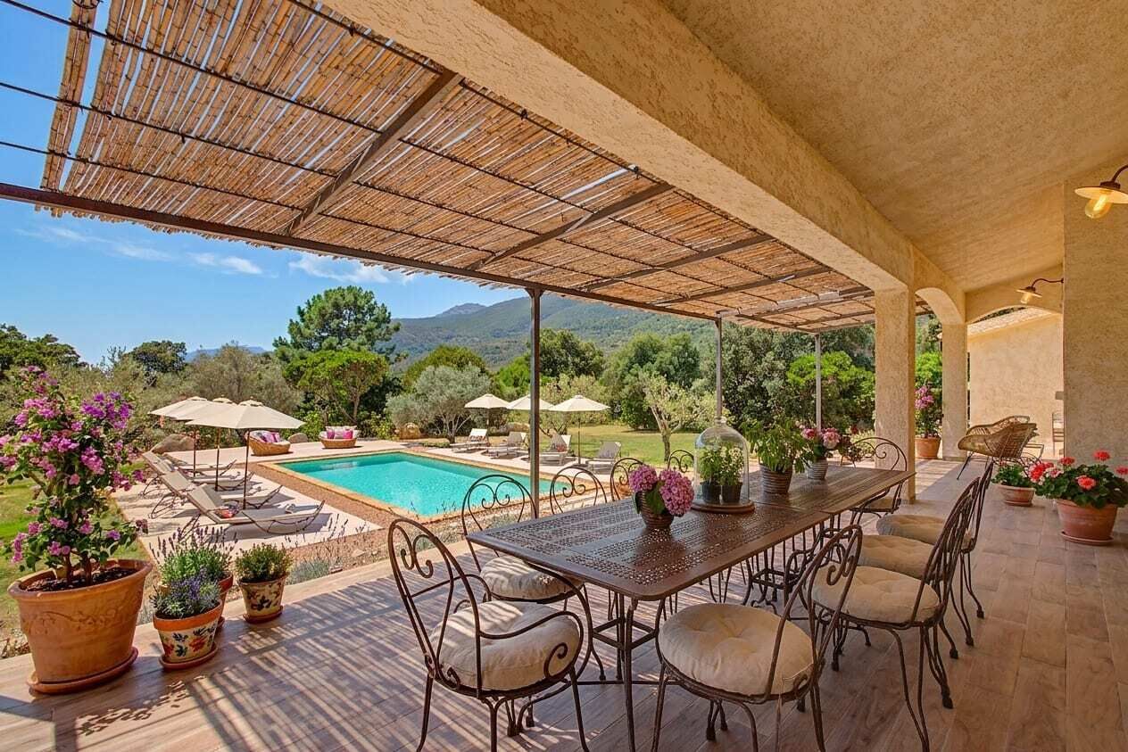 Eine Terrasse im Freien mit Pool, umgeben von Kübelpflanzen und Gartenmöbeln.