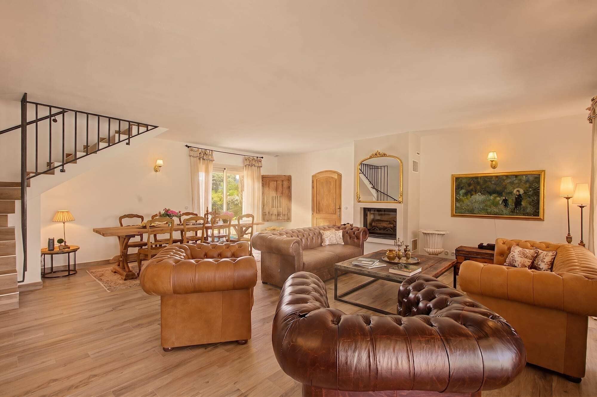 A spacious living room with a staircase, a dining area, and a fireplace.
