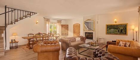 A spacious living room with a staircase, a dining area, and a fireplace.