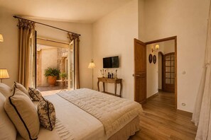 Ein Schlafzimmer mit einem Bett, einem Fernseher, einem Nachttisch und einer Tür zu einem anderen Raum.