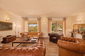 A spacious living room with leather sofas, a coffee table, and a painting on the wall. - Ô · Ô1 L'Aube Collection — 5-bedroom villa with private pool, Lecci, Southern Corsica (San-Gavino-di-Carbini)