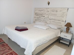 A neatly made bed with a white duvet, two pillows, and a folded red and gray blanket on the side. - Vrbo Property (tunis)