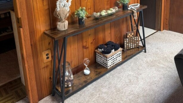 A wooden wall with a framed painting of deer, a console table with decorative items, and a carpeted floor. - Cozy cabin on All Sports Lake with private beach! Close to ski resorts & trails (Atlanta)