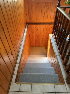 A wooden staircase with a carpeted landing and a handrail. - Cozy cabin on All Sports Lake with private beach! Close to ski resorts & trails (Atlanta)
