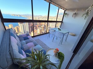 A high-rise apartment with a large balcony, a seating area with a sofa, a dining table, and potted plants. - Breathtaking panoramic view above the city (Benidorm)