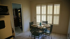 Une cuisine équipée d’une table à manger pour quatre personnes, d’un réfrigérateur et d’une fenêtre avec des stores.