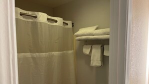Un baño con cortina de ducha, toallero con toallas y un inodoro.