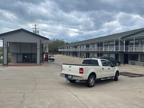A parking lot with a white pickup truck, a building with a balcony, and a sign with the number 3033.