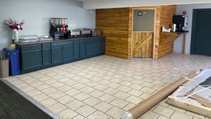 Una cocina con armarios de madera, una encimera con electrodomésticos y suelo de baldosas.