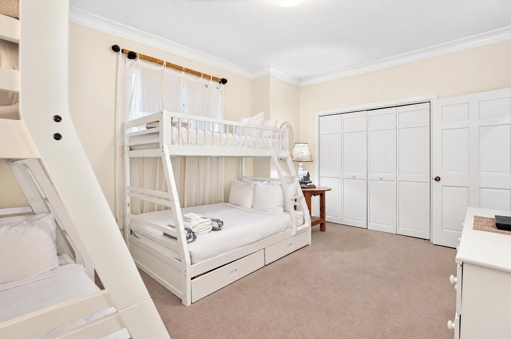 A bedroom with bunk beds, a desk, a chair, a lamp, and a wardrobe.