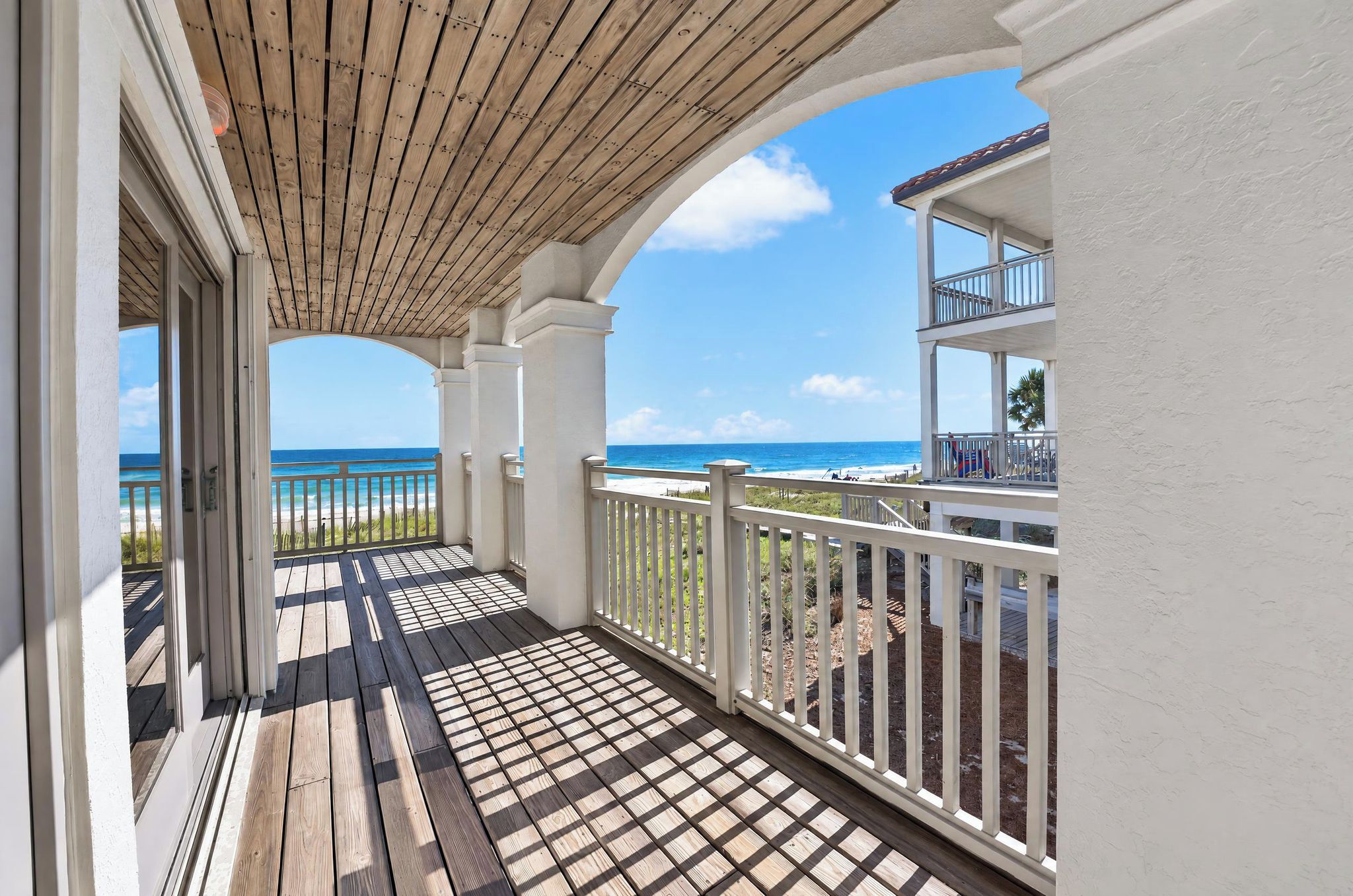 A wooden deck with a view of the beach and ocean.