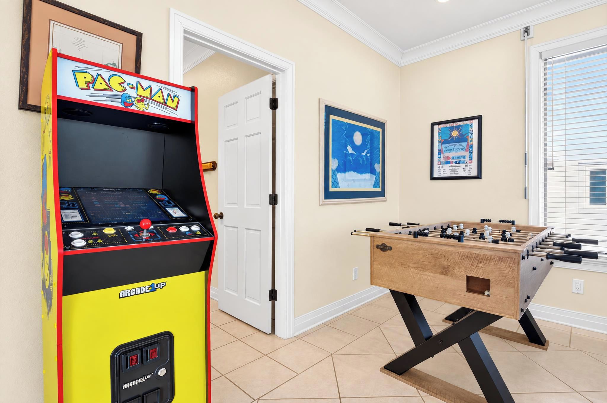 Una habitación con mesa de fútbol y una máquina recreativa antigua.