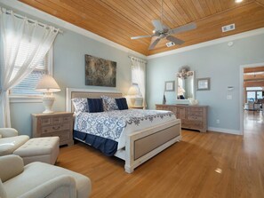 A bedroom with a large bed, bedside tables, a ceiling fan, and a view of the adjacent living area. - A Sandcastle! Beach Front, Hot Tub, Community Pool, Beach Gear Credit! (St. George Island)