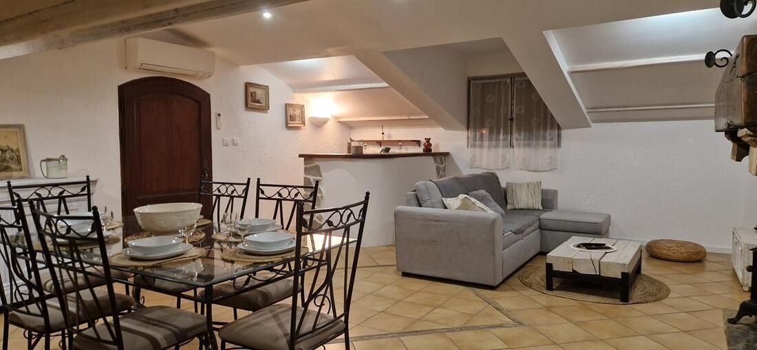 Un coin repas avec une table dressée pour quatre personnes, un canapé gris et une petite table basse.