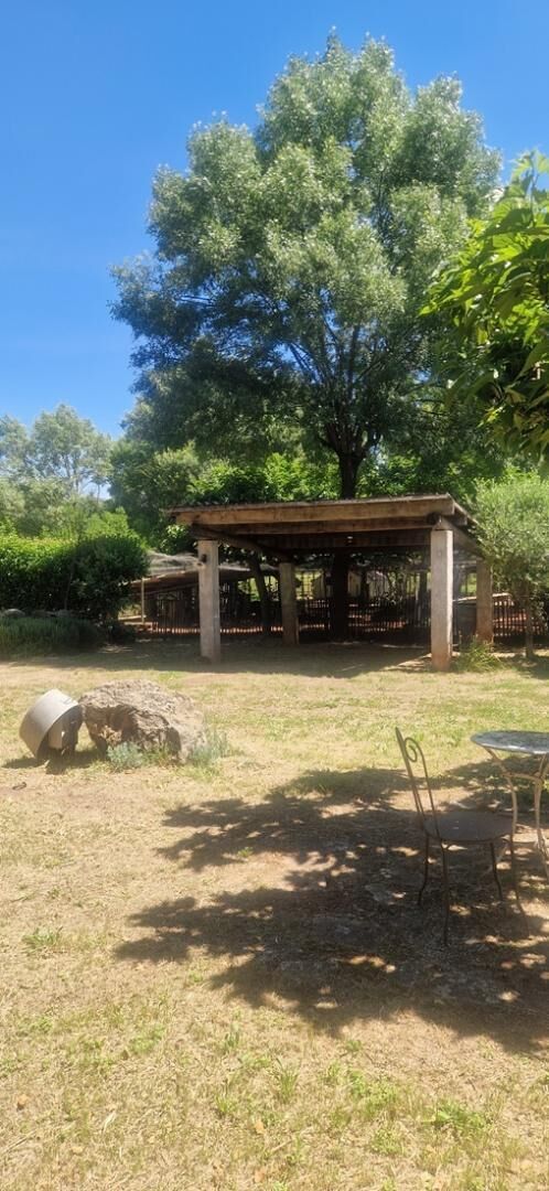 Un espace extérieur abrité, doté d’une pergola, d’une table et de chaises.