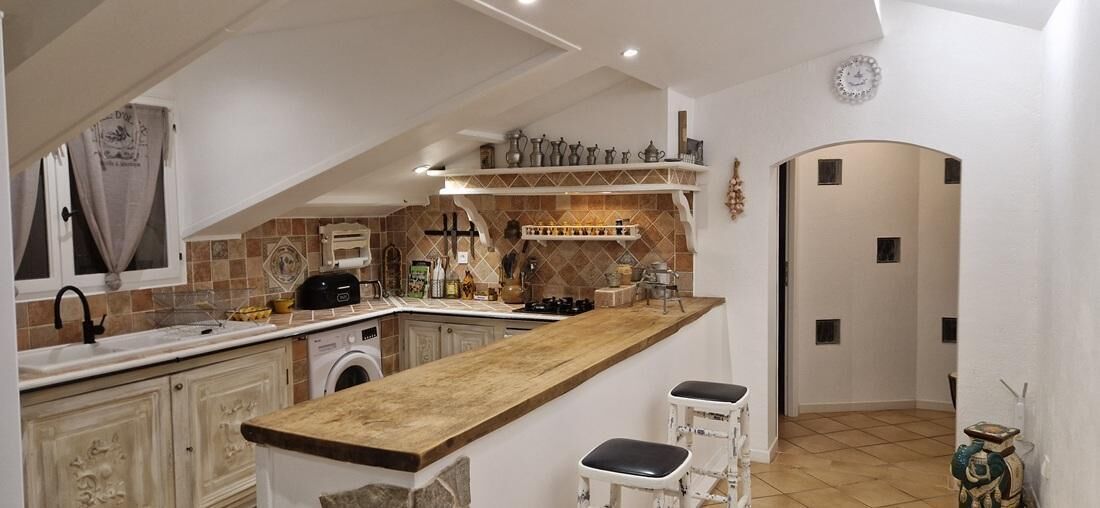Une cuisine avec un plan de travail en bois, un lave-linge et un évier.