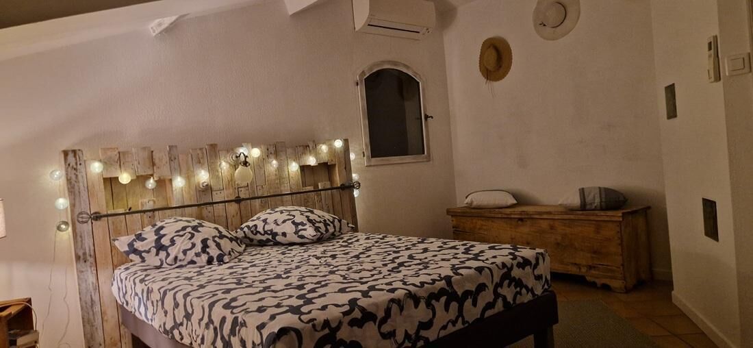 Een slaapkamer met een bed, nachtkastje en een klein raam.