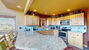 A kitchen with granite countertops, wooden cabinets, a built-in microwave, and an oven. - Master ensuite | Wood burning fireplace | Bike & Ski Gear Storage | Byrd's Nest (Angel Fire)
