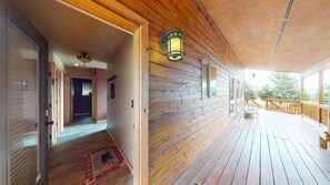 A wooden cabin with a porch, a door leading to an interior hallway, and a window overlooking greenery. - Master ensuite | Wood burning fireplace | Bike & Ski Gear Storage | Byrd's Nest (Angel Fire)