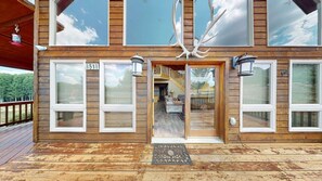 A wooden cabin with large windows, a deck, and a number '51' sign. - Master ensuite | Wood burning fireplace | Bike & Ski Gear Storage | Byrd's Nest (Angel Fire)