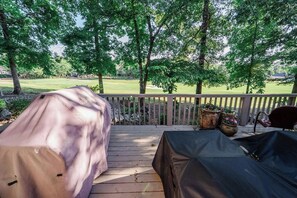 Eine Terrasse im Freien mit überdachter Grillgelegenheit, Holzlattenzaun und Kübelpflanzen.