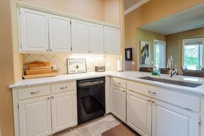 A kitchen with white cabinets, a dishwasher, a countertop with a sink, and a sign that says 'HONEY FOR SALE'. - Fairway View on Isabella Golf Course (Hot Springs Village)